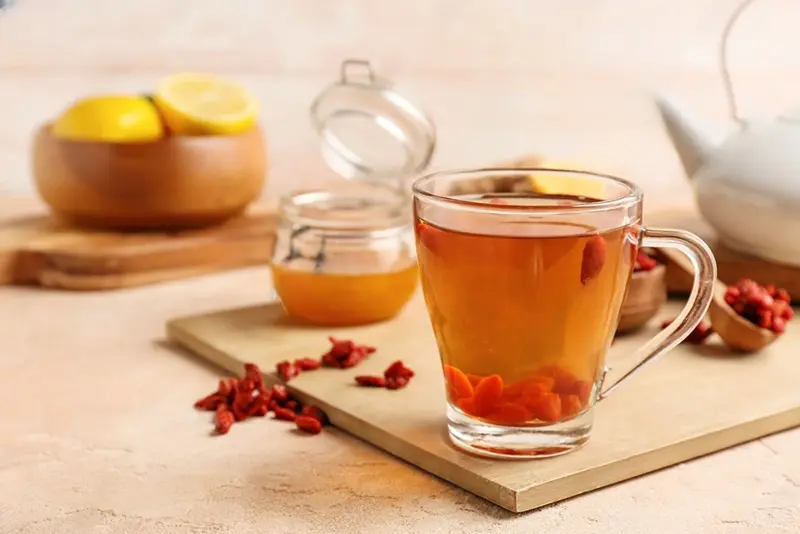 Taza de té con baya de Goji y miel en mesa
